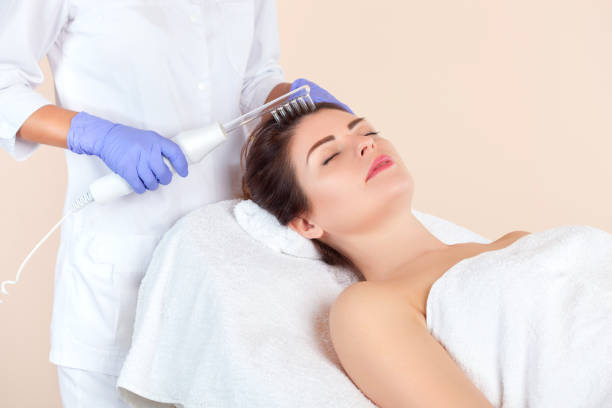 o cosmetólogo faz a terapia microcorrente contra a queda de cabelo em um salão de beleza. cosmetologia e cuidados profissionais com a pele. - capillary - fotografias e filmes do acervo