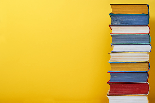 Big book stack on yellow background Education concept Copy space