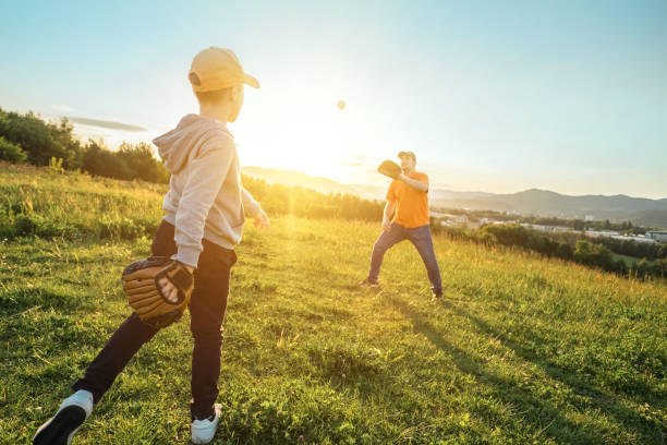 istock Father and son playing in baseball. Playful Man teaching Boy baseballs exercise outdoors in sunny day at public park. Family sports weekend. Father's day. 1247783236