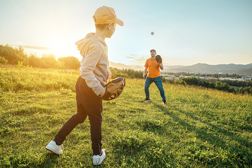 Father and son playing in baseball. Playful Man teaching Boy baseballs exercise outdoors in sunny day at public park. Family sports weekend. Father's day.