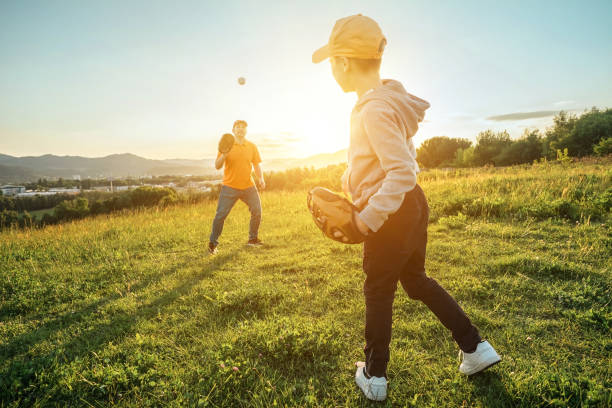 istock Father and son playing in baseball. Playful Man teaching Boy baseballs exercise outdoors in sunny day at public park. Family sports weekend. Father's day. 1247783305