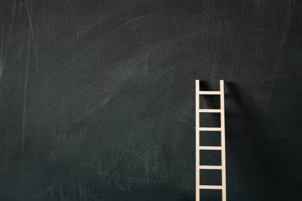 istock wooden ladder over classroom blackboard background 1247783446