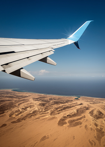 Commercial airplane flying over the Sahara desert and Red Sea near Marsa Alam, Egypt, Africa.