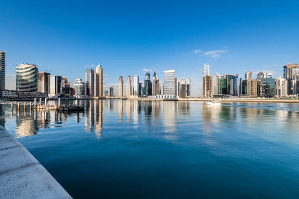 Dubai, United Arab Emirates - Offshore shot of skyscrapers on Dubai Marina. Image shot from a yacht that was just leaving the Marina. Long focal length zooms into the towers. The tower with the twist is still under construction. Several yachts can be seen moored in the Marina. Image shot in the late afternooon sunlight; horizontal format. Copy Space. Note to Inspector: There are more than 3 buildings in the image; there are also more than three signs and logos, but no sign is more prominent than the other.