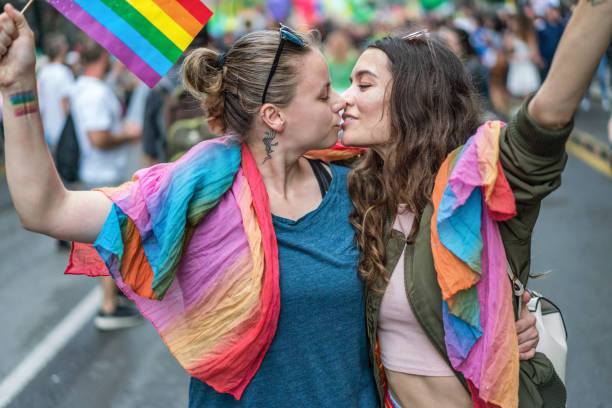 pareja femenina besándose - homosexual rainbow gay pride flag flag fotografías e imágenes de stock