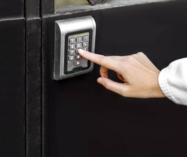 istock female hand dials the access code on the electronic lock by pressing a index finger on button, closeup of the security lock on black iron gate with copy space. 1247804174