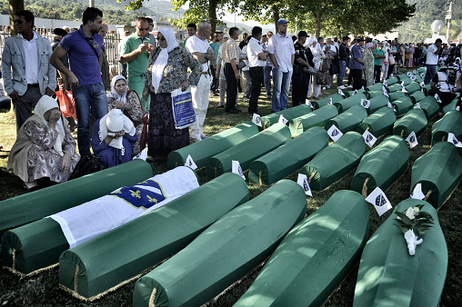 Since 2005, in July, people from all over the world have been arriving in Bosnia and Herzegovina to attend the funeral ceremony held for the victims of the genocide at the Potočari Memorial.\nFour hundred Dutch UN soldiers had the task of defending the territory of Srebrenica, declared an area under international protection. But it didn't happen. When Serbian troops on 11 July 1995 occupied Srebrenica under the command of General Mladic, UN soldiers retreated here to their base in Potocari and did not defend the city. The UN commands did not make the fighters intervene to stop the Serbs thus allowing the massacre.\nThe coffins are covered with green canvas, inside there are the few remains of the killed person. A tag with a number remembers its name. Family members and relatives look for their loved one's coffin. They caress her, someone sits next to them and stays there for hours.