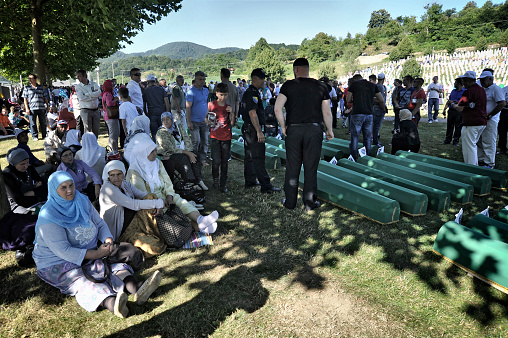 Since 2005, in July, people from all over the world have been arriving in Bosnia and Herzegovina to attend the funeral ceremony held for the victims of the genocide at the Potočari Memorial.\nFour hundred Dutch UN soldiers had the task of defending the territory of Srebrenica, declared an area under international protection. But it didn't happen. When Serbian troops on 11 July 1995 occupied Srebrenica under the command of General Mladic, UN soldiers retreated here to their base in Potocari and did not defend the city. The UN commands did not make the fighters intervene to stop the Serbs thus allowing the massacre.\nThe coffins are covered with green canvas, inside there are the few remains of the killed person. A tag with a number remembers its name. Family members and relatives look for their loved one's coffin. They caress her, someone sits next to them and stays there for hours.