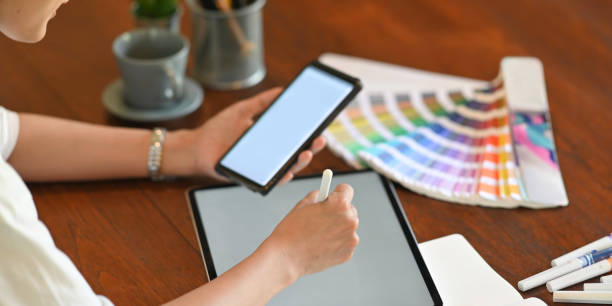 istock Cropped image of a woman's hands is holding a smartphone and drawing on a computer tablet. 1247808153