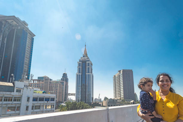 young Indian mother and 5 year old girl standing on rooftop with building backside