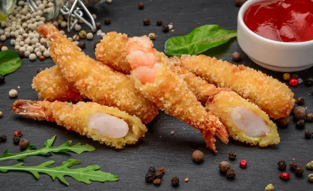 Fried Shrimps tempura with sweet chili sauce on black board stone