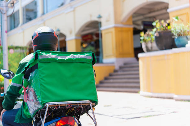 istock Takeaway, delivery boy on scooter with red isothermal backpack driving fast. Courier delivering food on motorbike to avoid evening traffic jams,24 hours delivery service from cafes and restaurants. 1247818018