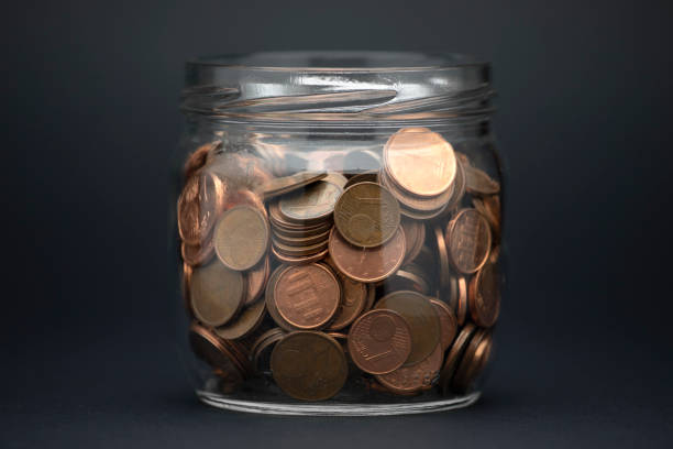 Glass jar with the coins on a black background Glass jar with coins on a black background for a savings concept deposit bottle stock pictures, royalty-free photos & images