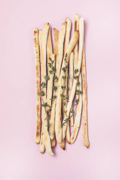 bâtonnets de fromage ou de pain maison avec des bâtons de pain croustillants de troupeaux avec le thym et le romarin sur le fond rose vue supérieure horizontale - twisted cheese biscuit pastry photos et images de collection