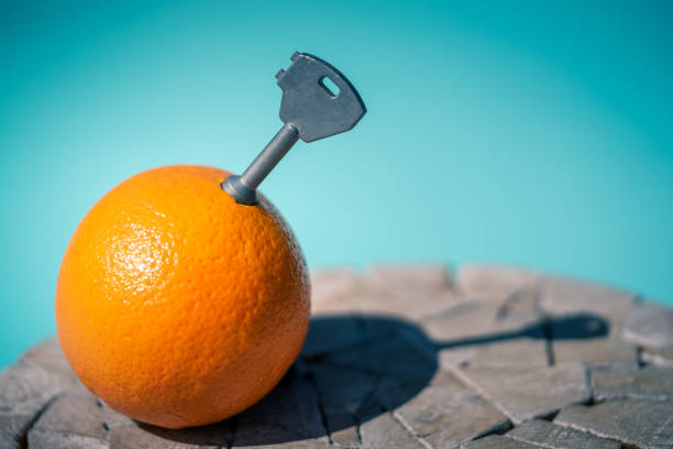 A Clockwork Orange a orange fruit on a wooden table with a key inside pulp. blue background navel orange photos stock pictures, royalty-free photos & images