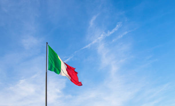 istock Italian flag in a blue sky with clouds 1247842947