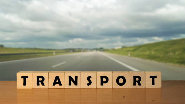 istock TRANSPORT concept message word on a wooden desk on cube blocks with a empty road background 1247844269