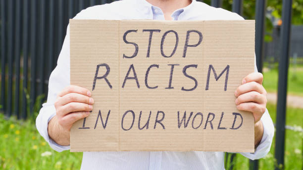 istock Stop racism concept. Unrecognizable white person holds sign with text against racist. 1247851267