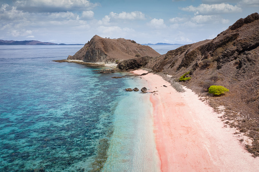 Pink Beach Komodo Island. Aerial view towards famous Pink Beach in the Komodo National Park. Natural pink colored beach towards clean coral reef water. Komodo National Park, Komodo island, Labuan Bajo, Flores, Indonesia, Southeast-Asia.