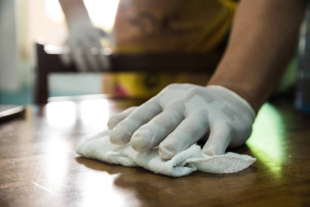 istock Man cleaning a table with a rag and rubber gloves at home 1247858332