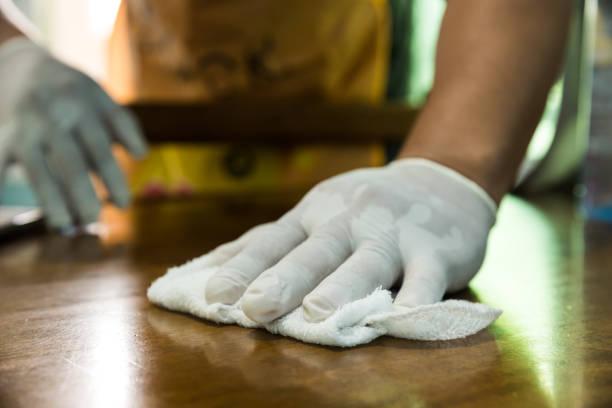 istock Man cleaning a table with a rag and rubber gloves at home 1247858337