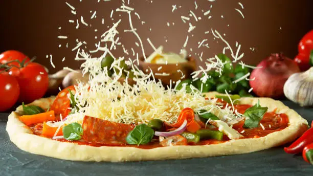 Falling mozzarella cheese on pizza, freeze motion. Italian traditional meal.