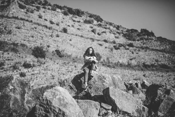 Beautiful Plus Size Young Smiling Woman In Pink Shirt Sitting on Stone inSummer Forest