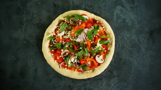 Top view of pizza meal preparation, raw ingredients inside. Italian traditional meal.