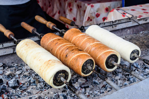 istock Four fresh Kurtos kalacs (Chimney Cakes) being cooked and glazed with sugar on rolls spinning and displayed for sale at a local Hungarian market stand, traditional food photographed with soft focus 1247864228