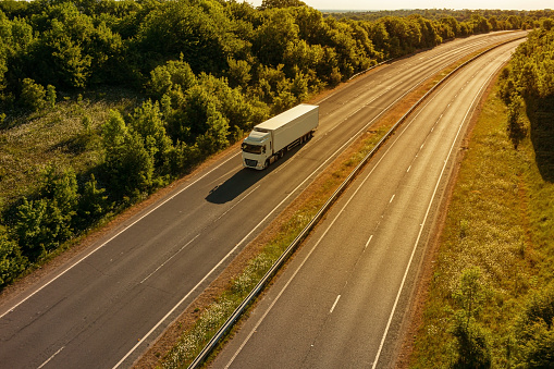 Single lorry in motion on empty motorway during sunset.