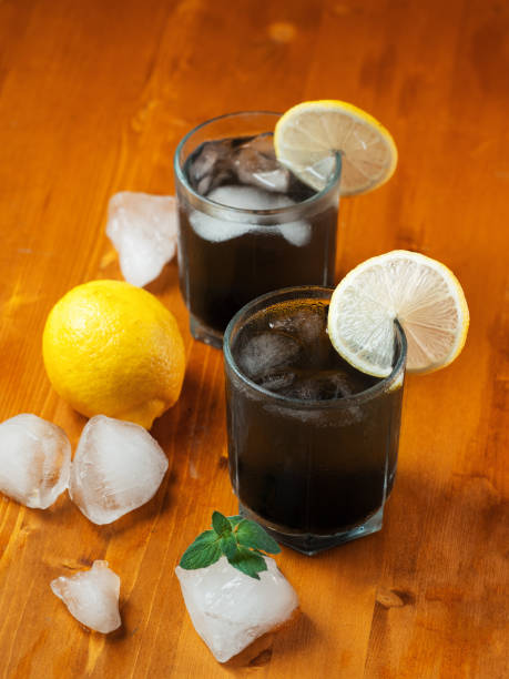 Black lemonade with mint, lemon, charcoal and ice on a wooden table