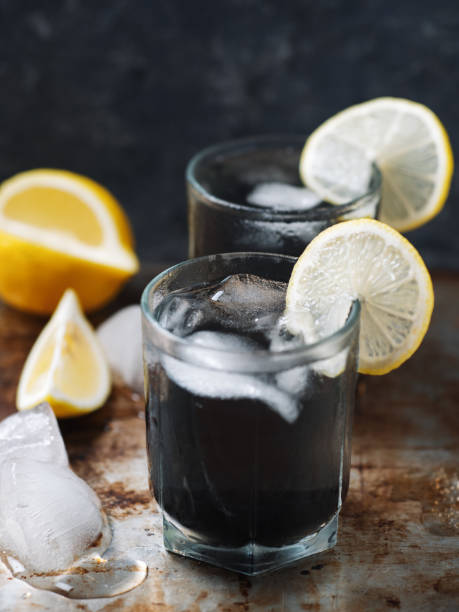 two glasses of summer lemonade with lemon and charcoal. refreshing ice detox drink