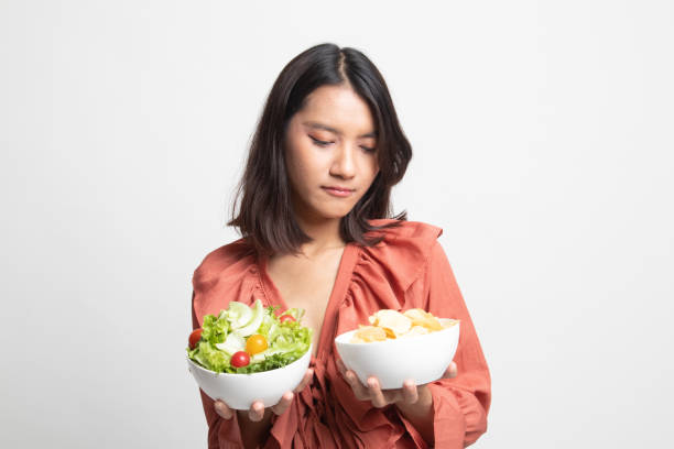 istock Young Asian woman with potato chips and salad . 1247888024