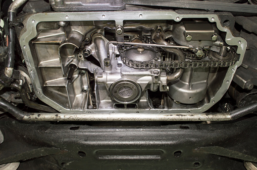 Bottom view of the internal combustion engine with the removed oil sump mounted on the car, the oil pump is visible