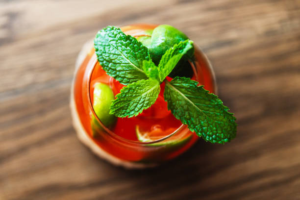 cocktail de fruits rouges mélangé avec du citron tranché et garni de feuilles de menthe fraîche verte. boisson aigre-douce combinée avec l’intensité de la liqueur et l’odeur fraîche de la menthe. les femmes peuvent boire. pour se détendre par u - sour taste green traditional culture lemon photos et images de collection