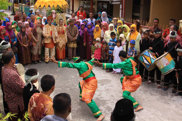 Traditional Silat dance at Minangkabau wedding, in Padang, West Sumatra, Indonesia. Village people dressed in festive clothes, dancers and music orchestra, attending public ceremony in the street.