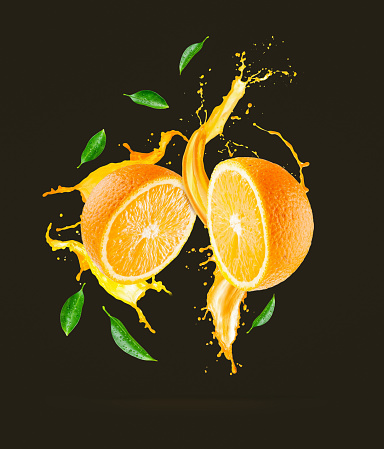 Juice splashes out from sliced orange on a black background