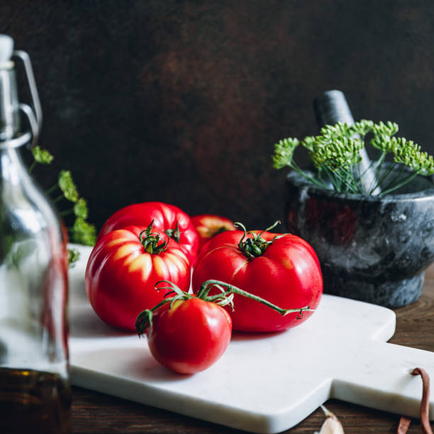 istock Ripe tomatoes on a white marble kitchen board. Cooking concept. 1247912140