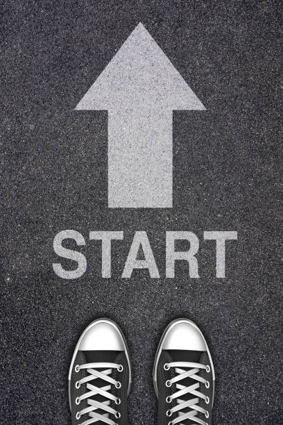istock Start background, top view. Shoes standing next start with arrow painted on ground 1247915804