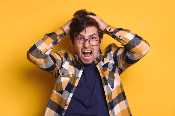 istock Frustrated handsome man in glasses pulling out his hair on yellow studio wall 1247921546