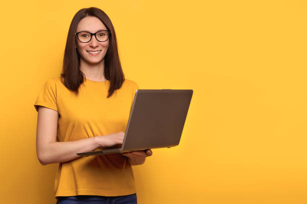 istock Smart beautiful young girl using laptop pc computer isolated on yellow background 1247921780