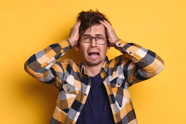 istock Despaired young man holding his head against yellow studio background 1247921804