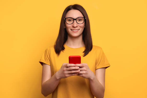 istock Happy caucasian girl holding cellphone and looking at the camera 1247926054
