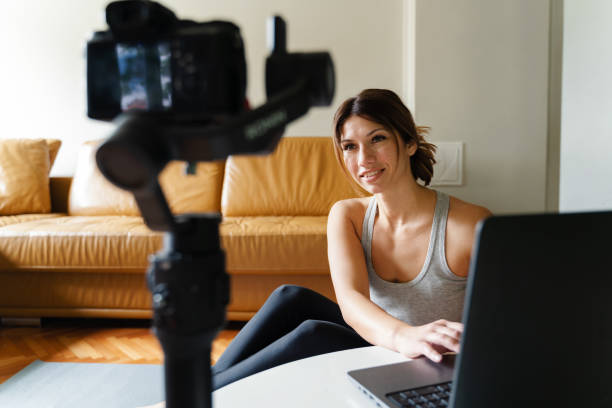 istock Young caucasian woman sitting at home beautiful instructor teaching online class working in the apartment talking in front of camera and laptop making video blog or vlog in day or morning 1247926214