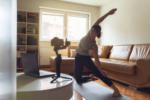 istock Young caucasian woman practicing yoga at home beautiful instructor teaching online class training in apartment standing in position asana in front of camera and laptop making video in day or morning 1247926274