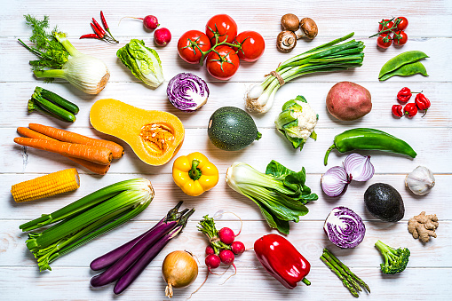 Healthy food: large group of  multicolored fresh organic vegetables shot from above on white table. Vegetables included in the composition are kale, tomatoes, squash, asparagus, potato, celery, eggplant, carrots, lettuce, edible mushrooms, bell peppers, cauliflower, ginger, radish, avocado, onion, chili pepper, corn, among others. High resolution 42Mp studio digital capture taken with SONY A7rII and Zeiss Batis 40mm F2.0 CF lens