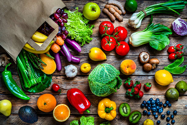 shopping bag filled with fresh organic fruits and vegetables shot from above on wooden table - vegetables table imagens e fotografias de stock