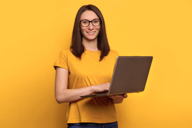 istock Smart beautiful young girl using laptop pc computer isolated on yellow background 1247933236