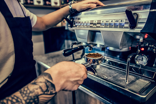 Barista holding a portafilter filled with grindered coffee beans