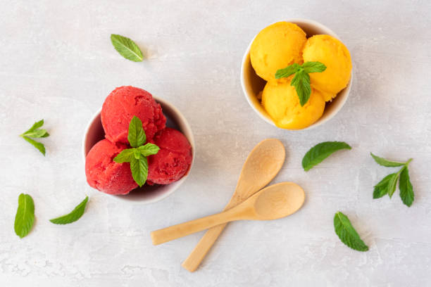 istock Ice cream scoops in bowls with strawberry and mango flavors. Top view 1247945128
